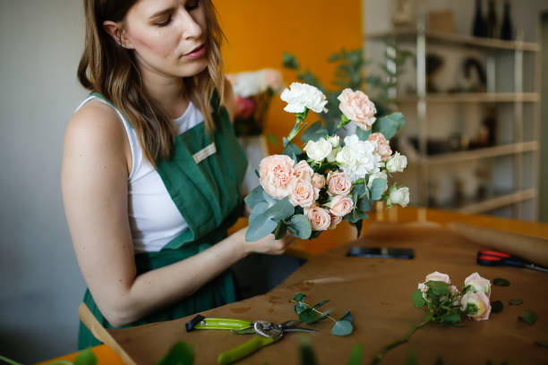 A beautiful real girl in a flower shop makes a bouquet of flowers and craft paper. Green business with reusable and environmentally friendly tools and accessories